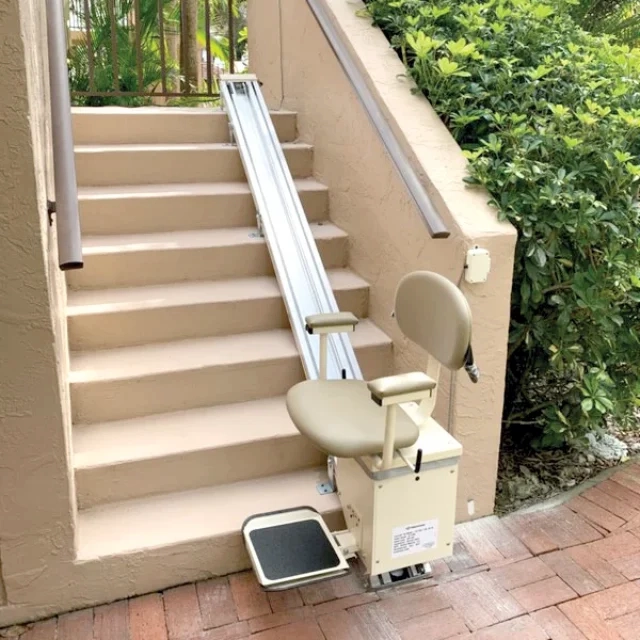 Weatherproof outdoor stairlift installed on exterior steps beside a landscaped entry