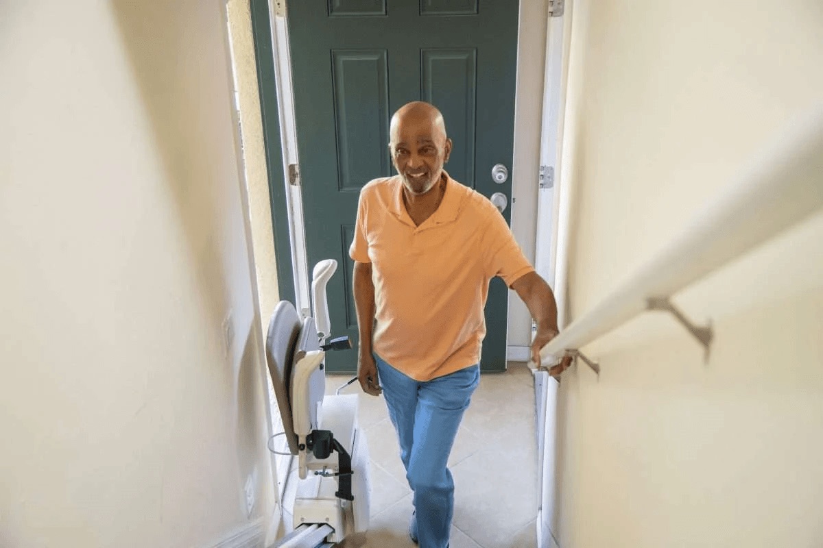 Homeowner using the staircase beside a folded stairlift